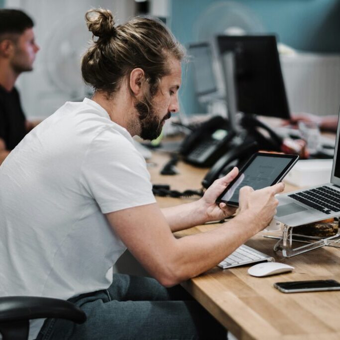 A man at a desk in the office, using a tablet